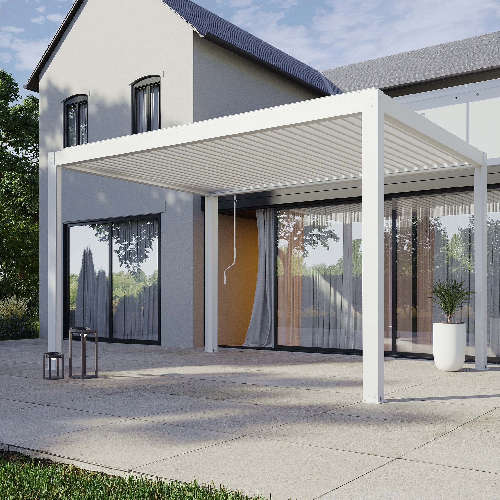A modern patio showcases the PergoSTET Plus 3m x 4m white rectangular pergola with a built-in drainage system, attached to a gray house. It is complemented by large windows and a potted plant.